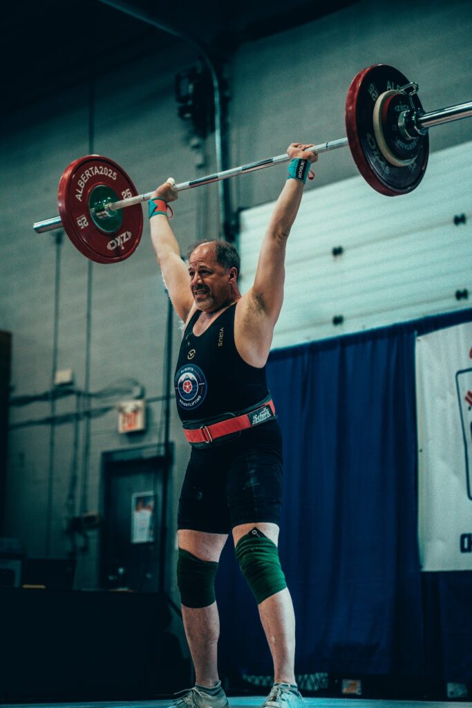 Masters weightlifter Dan Schiff locking out a barbell overhead at a competition